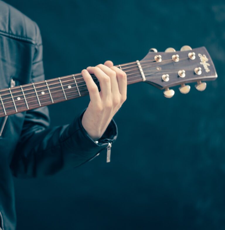 En gitarist som håller i en gitarr. Endast vänster arm på bild.
