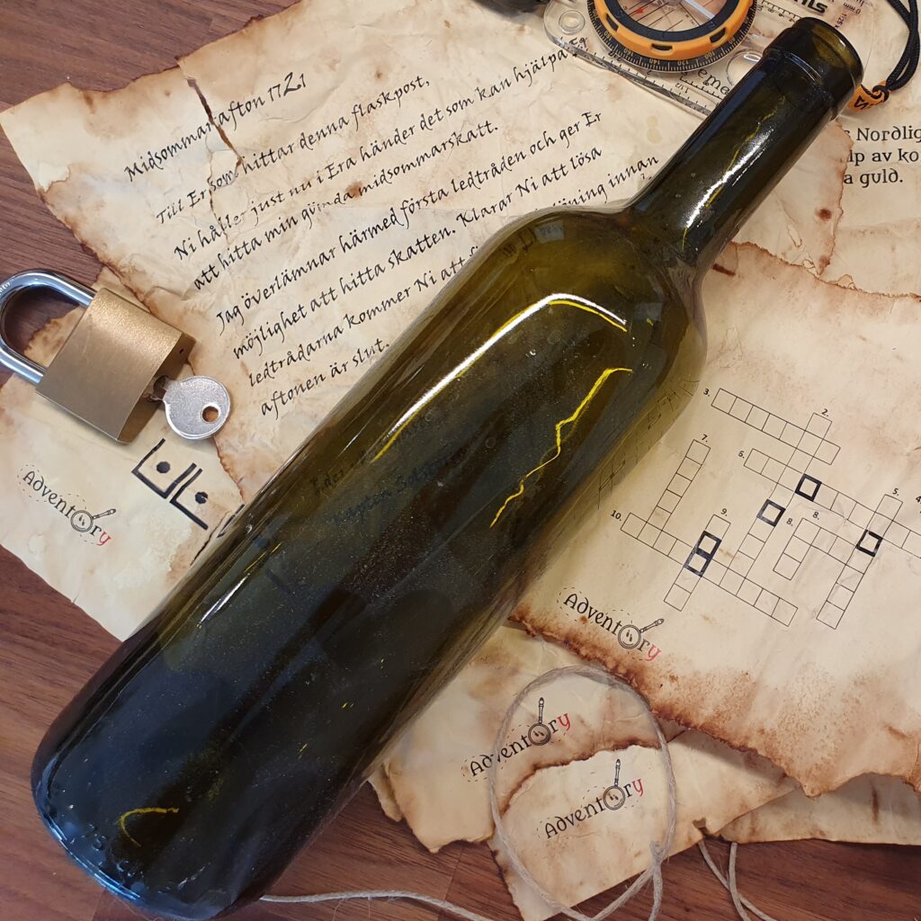 Delar från Adventprys Midsommaräventyr ligger på ett bord. flaskpost hänglås. Åldrade dokument.